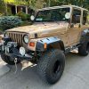 Three-quarter front view of a 1999 gold Jeep Wrangler Sport 4x4