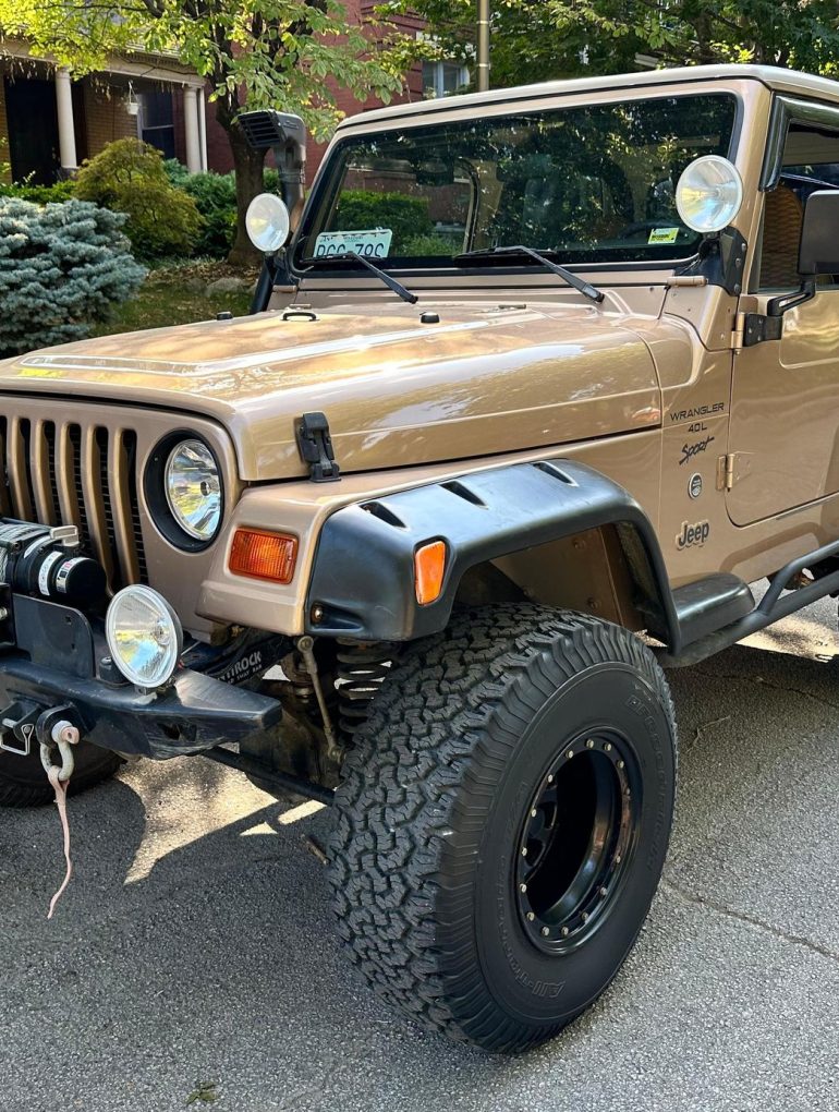 Three-quarter front view of a 1999 gold Jeep Wrangler Sport 4x4